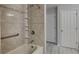 Tiled shower and tub area showcasing built-in shelves, complemented by a handrail for added accessibility and safety at 12878 Ari Ln, Fishers, IN 46037