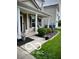 Charming covered front porch with black mulch landscaping beds, trimmed bushes, seasonal flowers, and tasteful decorations at 12993 E 131St St, Fishers, IN 46037