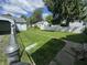 View of the large backyard, with white and blue outbuildings, and healthy green lawn at 144 S 7Th Ave, Beech Grove, IN 46107