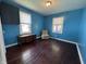 Bright blue bedroom with hardwood floors, two windows, and updated cabinet at 144 S 7Th Ave, Beech Grove, IN 46107