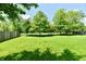 Spacious backyard with lush green grass, mature trees, and a wood fence for privacy at 16857 Palmetto Way, Noblesville, IN 46062