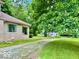 Charming home with stone facade, lush trees, and winding driveway to a distant blue house in the background at 1920 E Epler E Ave, Indianapolis, IN 46227