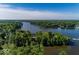 Expansive aerial view of a lush, tree-lined waterfront property on a serene lake under a clear, blue sky at 21218 Carlton Ct, Noblesville, IN 46062