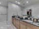 Bathroom with double sinks, wood cabinets, granite counters, and a glimpse into the walk-in closet at 222 N East St # 103, Indianapolis, IN 46204