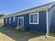 Home's back exterior with blue siding, white trim, and a sliding glass door leading to the yard at 223 N Coventry Dr, Anderson, IN 46012