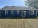 Back exterior of home featuring blue siding, white trim, and a well-maintained lawn at 223 N Coventry Dr, Anderson, IN 46012
