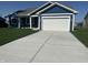 View of the home's front exterior with an attached garage, blue siding, and a concrete driveway at 223 N Coventry Dr, Anderson, IN 46012