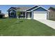 Charming single-story home with blue siding, a well-manicured lawn and a bright white garage door at 223 N Coventry Dr, Anderson, IN 46012