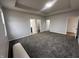 Large main bedroom featuring tray ceiling, soft carpet, and multiple doorways at 223 N Coventry Dr, Anderson, IN 46012