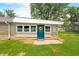 Charming home features a teal colored back door with a wreath, a manicured lawn and stone accents at 3027 Griffa Ave, Columbus, IN 47203