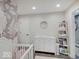Bedroom with white crib, dresser, and playful wallpaper at 3659 Watson Rd, Indianapolis, IN 46205