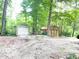 Two storage sheds, one with a roll-up door, sit on a gravel area surrounded by trees at 4419 Liberty Loop Rd, Martinsville, IN 46151