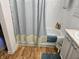 Clean bathroom featuring a bathtub with shower, tile walls, vanity and wood look flooring at 4962 Potomac Square Pl, Indianapolis, IN 46268