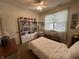 Bright bedroom with a white bed, bookshelf, ceiling fan, and a large window with curtains at 5486 Lipizzan Ln, Plainfield, IN 46168