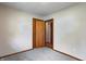 Simple bedroom with neutral walls, gray carpet, and a wooden closet door at 5941 North St, Stilesville, IN 46180