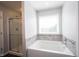 Bathroom showcases a large soaking tub with shower, glass door, and a window for natural light at 635 Sonoma Ln, Greenfield, IN 46140