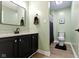 A bright bathroom featuring pale green walls, dark vanity and vinyl flooring at 6822 Woodford Ln, Indianapolis, IN 46237