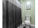 A small bathroom featuring a shower with a dark shower curtain and light green walls at 6822 Woodford Ln, Indianapolis, IN 46237