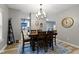 Open dining area with hardwood floors, a modern chandelier, and views to the kitchen and living spaces at 6822 Woodford Ln, Indianapolis, IN 46237