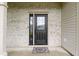 Close-up of the front door with decorative glass, brick surround, and stylish welcome mat at 6822 Woodford Ln, Indianapolis, IN 46237
