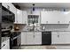Modern kitchen featuring gray countertops, a black oven, and sleek white cabinetry at 6822 Woodford Ln, Indianapolis, IN 46237