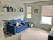 A cozy room includes a blue sofa bed, shelving, and two sunny windows at 6824 W Philadelphia Dr, McCordsville, IN 46055