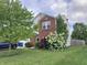 A well-manicured front yard with flowering bushes, a mature tree, and a partial view of the home's brick facade at 6824 W Philadelphia Dr, McCordsville, IN 46055