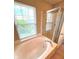 Bright bathroom features a soaking tub next to a glass door shower under a window at 6924 Havenmoor Pl, Indianapolis, IN 46250