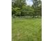 Lush green backyard with a white picket fence, mature trees, and expansive green lawn at 8130 Winterset Cir, Indianapolis, IN 46214