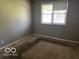 Vacant bedroom featuring neutral walls, worn carpet, and a bright window at 825 W Auman Dr, Carmel, IN 46032