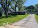 Ranch style home with a front yard and a long driveway leading to a detached garage at 825 W Auman Dr, Carmel, IN 46032