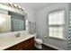 Bright bathroom featuring a wood vanity, large mirror, and a patterned shower curtain at 938 Weeping Way Ln, Avon, IN 46123