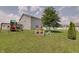 Spacious backyard featuring lawn, playset, mature tree, and white picket fence at 951 Gondola Run, Greenfield, IN 46140