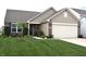 Inviting single-Gathering home boasts a well-kept lawn, tidy garden beds, brick details, and an attached garage at 10731 Jimmy Lake Dr, Indianapolis, IN 46239