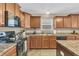 A kitchen with brown cabinets, tile floors, and black appliances at 10731 Jimmy Lake Dr, Indianapolis, IN 46239