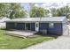View of the home's back exterior, featuring a deck, sliding glass door, and gravel driveway at 1082 Galaxie Dr, Greenwood, IN 46142