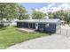 View of the home's back exterior, featuring a deck, sliding glass door, and gravel driveway at 1082 Galaxie Dr, Greenwood, IN 46142