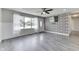 Bright living room boasts new gray flooring, fan, brick accent wall with mounted television, and large front window at 1082 Galaxie Dr, Greenwood, IN 46142