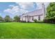 Expansive backyard with lush green lawn and charming home exterior featuring a covered porch and mature trees at 13145 Roma Bnd, Carmel, IN 46074