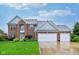 Stunning two-story brick home featuring a three-car garage and well-manicured front lawn with landscaping at 13145 Roma Bnd, Carmel, IN 46074