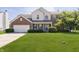 Charming two-story home featuring brick and siding exterior, manicured lawn and mature trees at 14135 Nicholas Dr, Carmel, IN 46074