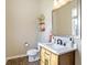 Elegant powder room featuring wood-look flooring, a modern vanity, and a stylish mirror with decorative accents at 15116 Fenchurch Dr, Westfield, IN 46074