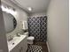 Updated bathroom with modern vanity, round mirror, and shower with patterned curtain at 1718 South Dr, Columbus, IN 47203