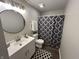 Modern bathroom featuring a vanity, round mirror, and shower with patterned curtain at 1718 South Dr, Columbus, IN 47203