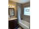 Bathroom featuring a vanity with storage, a bathtub with a shower curtain, and a glass block window at 1931 E 68Th St, Indianapolis, IN 46220