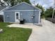 View of the property's detached blue garage with a concrete driveway, back door, and grill at 1931 E 68Th St, Indianapolis, IN 46220