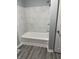 The bathroom features an updated tub with white marble-style tiled walls and updated flooring at 23 S Holmes Ave, Indianapolis, IN 46222