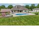 A sprawling backyard with a sparkling blue swimming pool, a covered structure, lush grass, and mature trees at 2825 S State Road 267, Plainfield, IN 46168