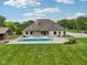 A sprawling backyard with a sparkling blue swimming pool, a covered structure, lush grass, and mature trees at 2825 S State Road 267, Plainfield, IN 46168