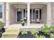 Inviting front porch with brick facade, decorative columns, and flower planters, enhancing curb appeal at 3251 Amber Way, Bargersville, IN 46106